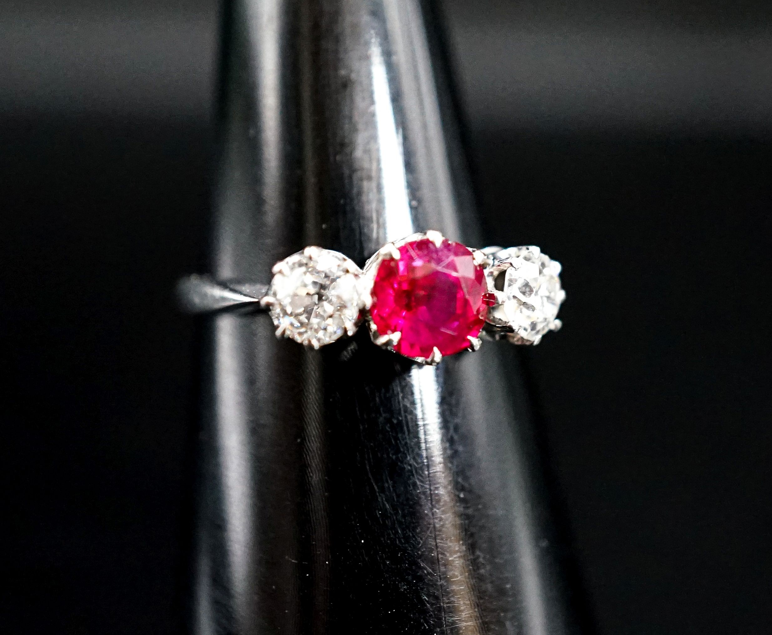 A white metal single stone ruby and two stone diamond ring, size L/M, gross weight 3 grams.